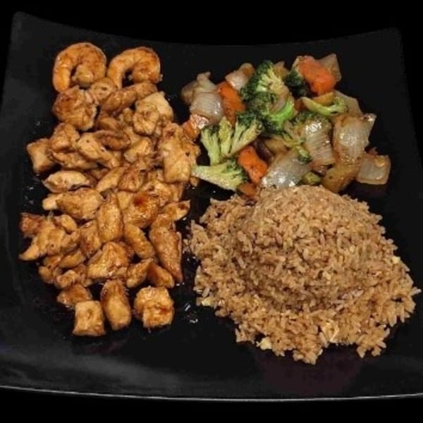 Hoshi Japanese Steakhouse's chicken and shrimp hibachi with fried rice and mixed vegetables on a black plate.