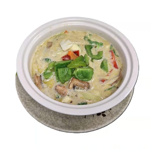 Creamy Japanese soup with green bell peppers, mushrooms, and other vegetables in a white bowl.